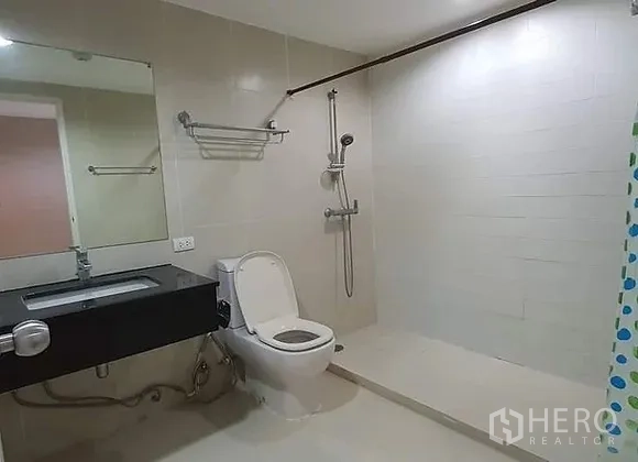 คอนโด ให้เช่าในHuai Khwang, Bangkok - ห้องน้ำที่สอง พร้อมโซนอาบน้ำแบบวอล์กอิน โถสุขภัณฑ์ และเคาน์เตอร์ซิงก์สีดำ