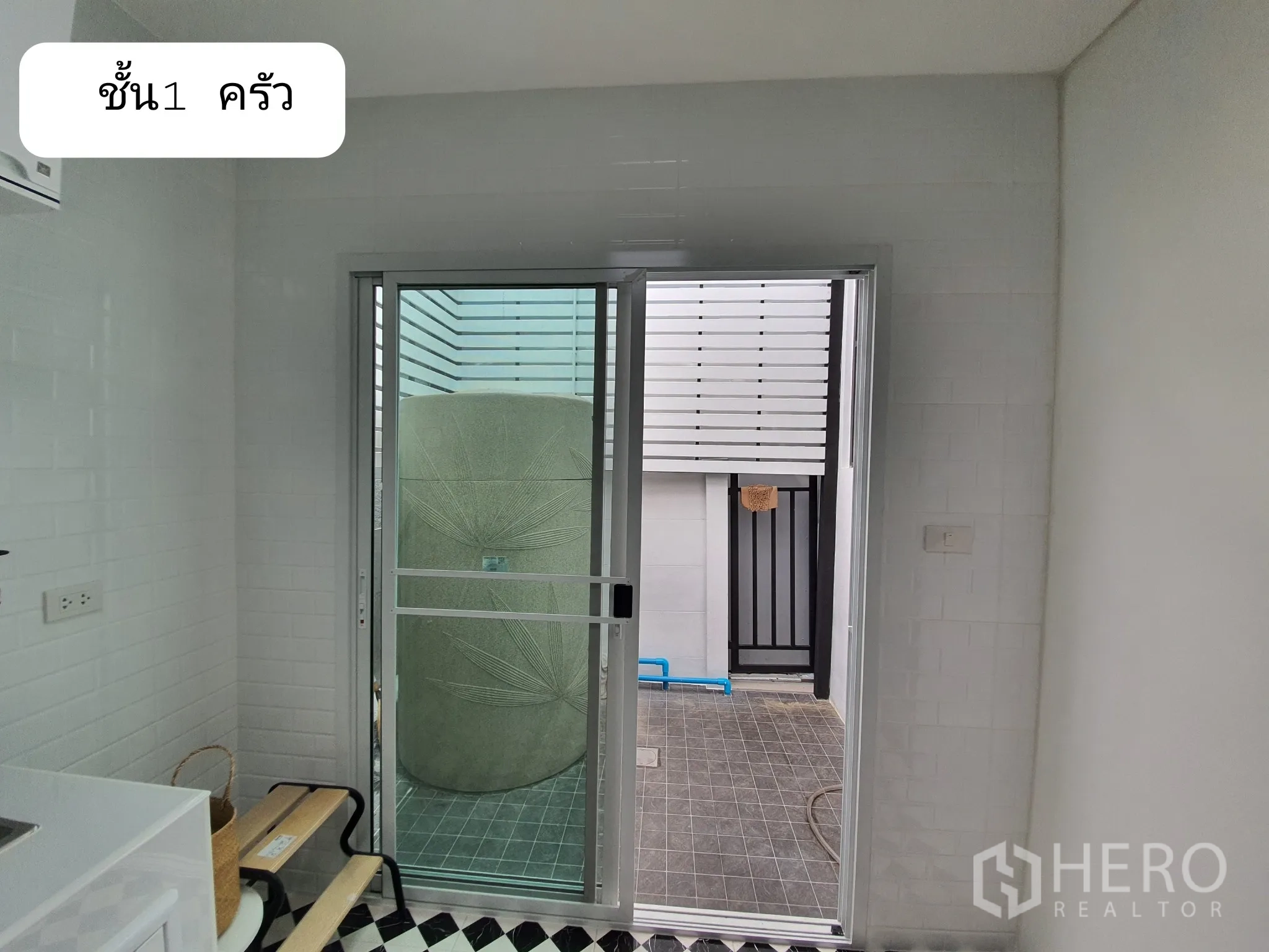 带办公室的家 出租或出售在Prawet, Bangkok - 一层厨房通往小型后院的推拉门，可见户外水塔。