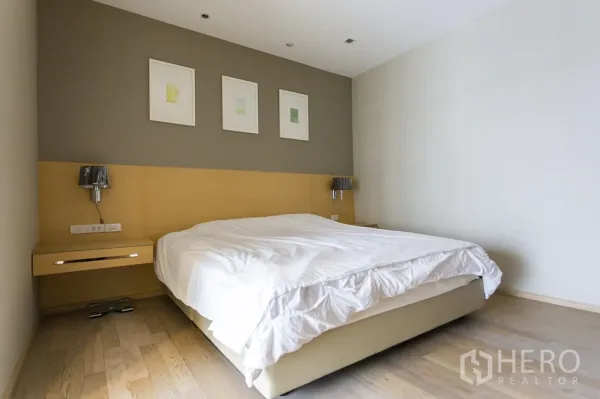 Condominium for rent in Khlong Toei, Bangkok - Calm bedroom with king-size bed, wood floors and wall-mounted bedside lamps.
