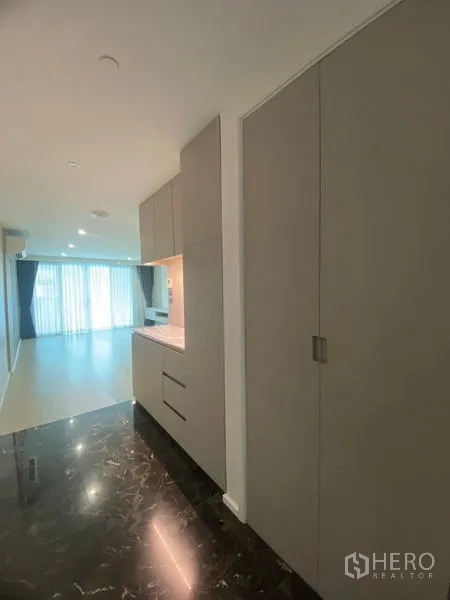 Apartment for rent in Watthana, Bangkok - Entry hallway with built‑in storage cabinets, marble threshold and view toward the bright living area.