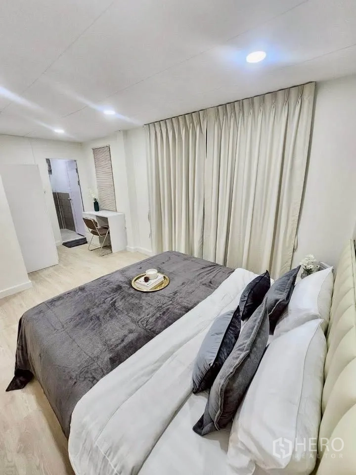 บ้านเดี่ยว for rent in Huai Khwang, Bangkok - ห้องนอนพร้อมเตียงหัวบุ โต๊ะทำงาน และประตูเข้าสู่ห้องน้ำ