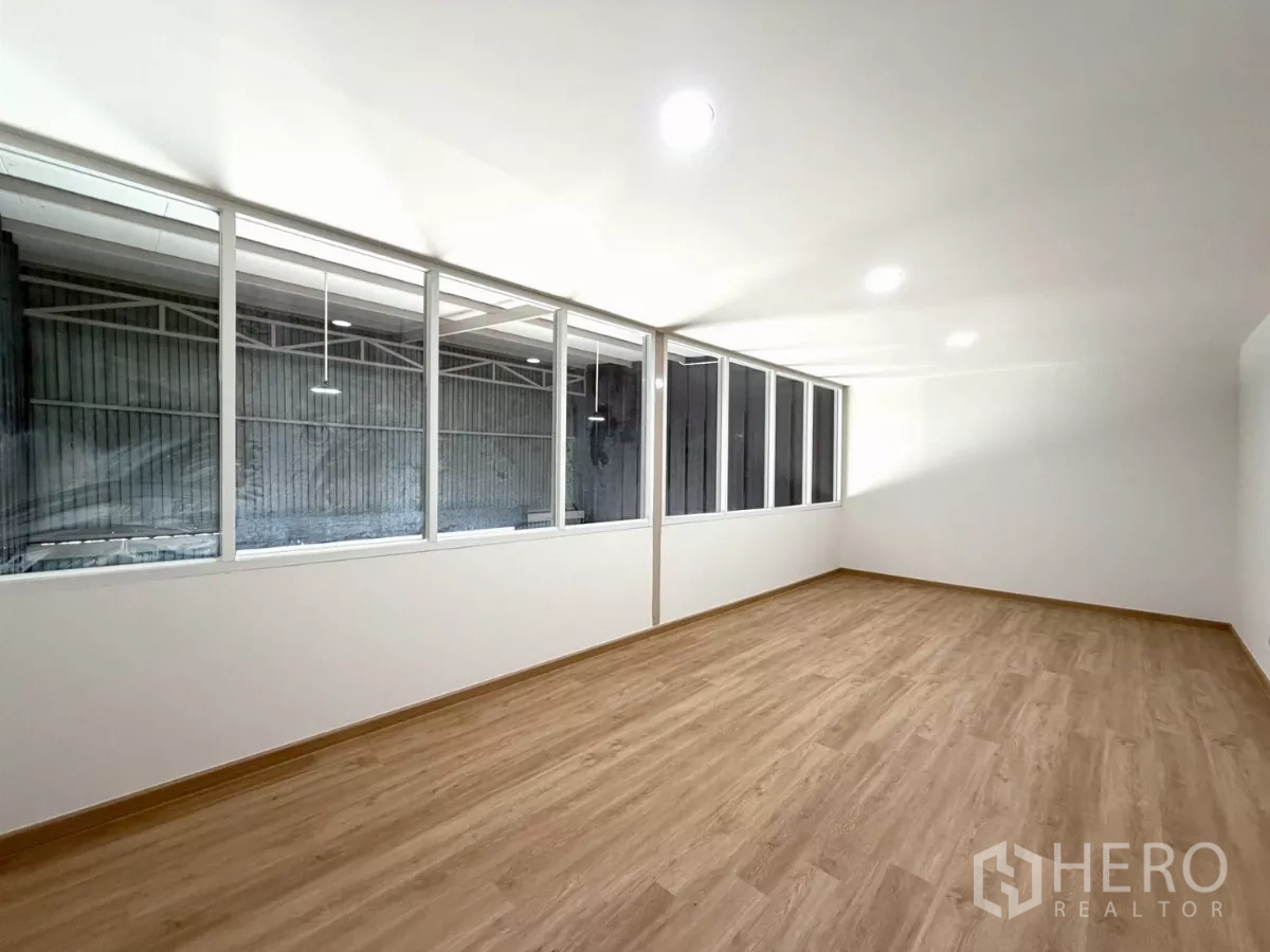Warehouse for rent in Suan Luang, Bangkok - Large office room with ceiling lights, laminate flooring and a sliding door above the warehouse area.