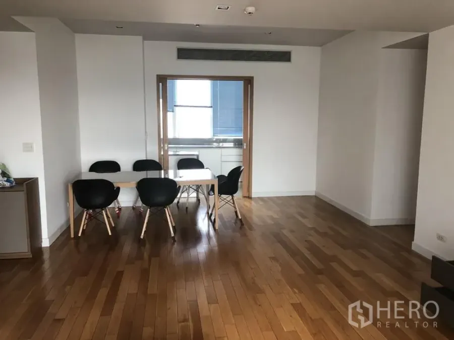 Condominium for rent in Khlong Toei, Bangkok - Open dining area with six-seat table on wooden flooring, facing sliding door to the kitchen.