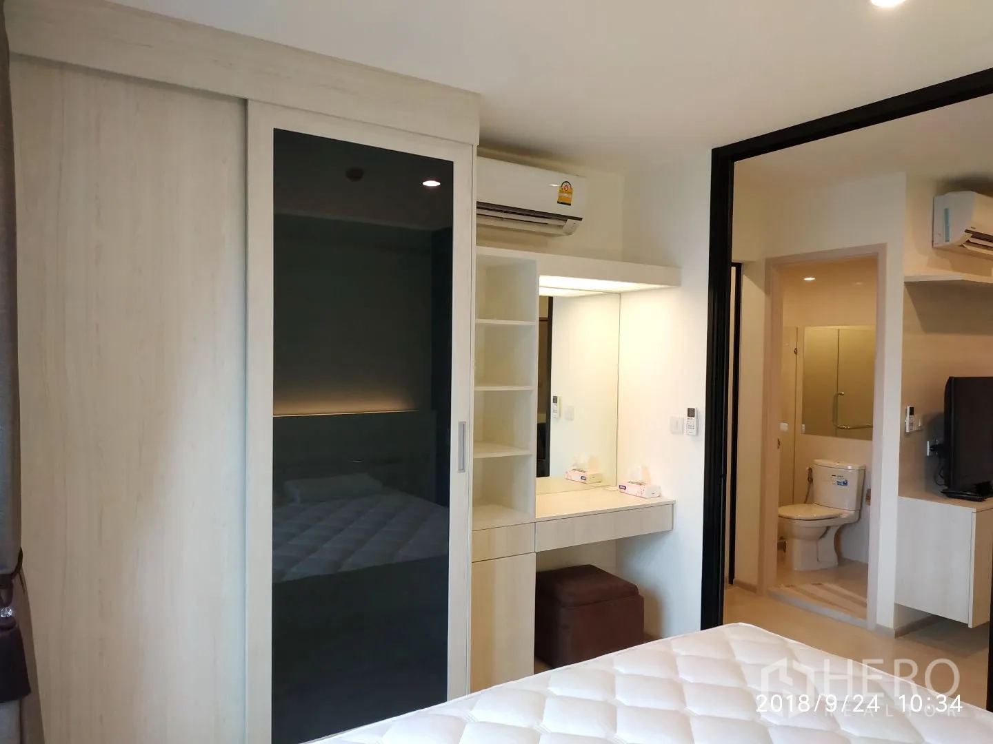 คอนโด ให้เช่าในHuai Khwang, Bangkok - ห้องนอนพร้อมตู้เสื้อผ้าบานเลื่อน โต๊ะเครื่องแป้ง และเครื่องปรับอากาศ ใกล้ประตูทางเข้าห้องน้ำ.