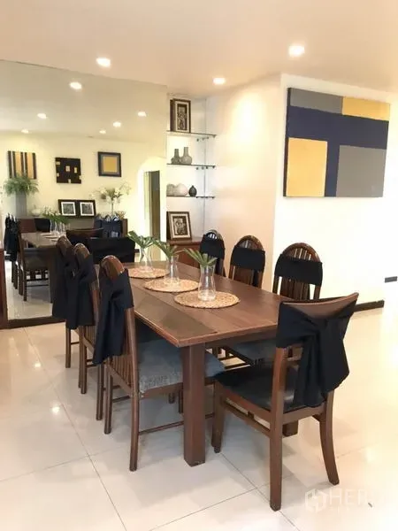 Detached House for rent in Phra Khanong, Bangkok - Eight-seat wooden dining table beside wall art and a large mirrored wall.