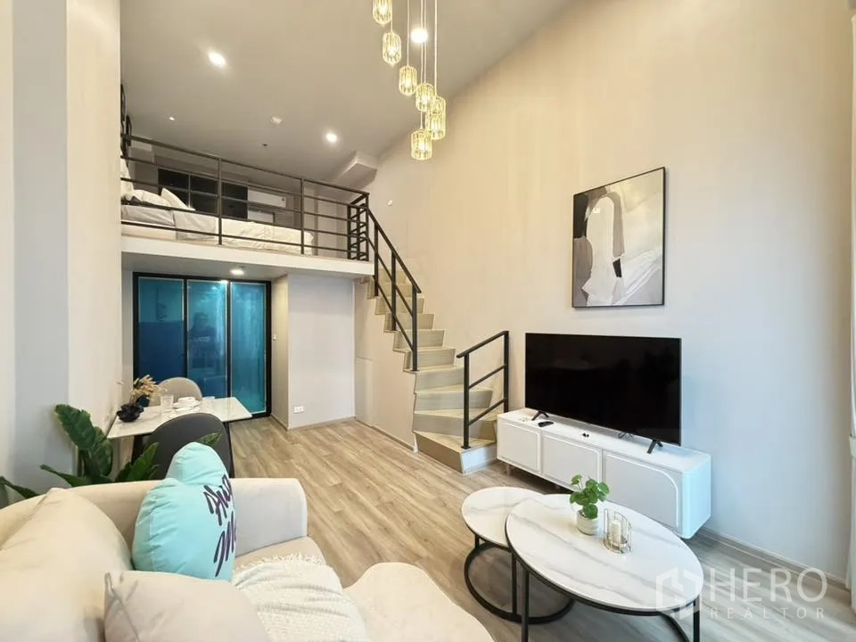 公寓 for rent in Khlong Toei, Bangkok - 现代公寓的阁楼式客厅，设有夹层卧室、楼梯、沙发、电视柜、用餐角和吊灯。