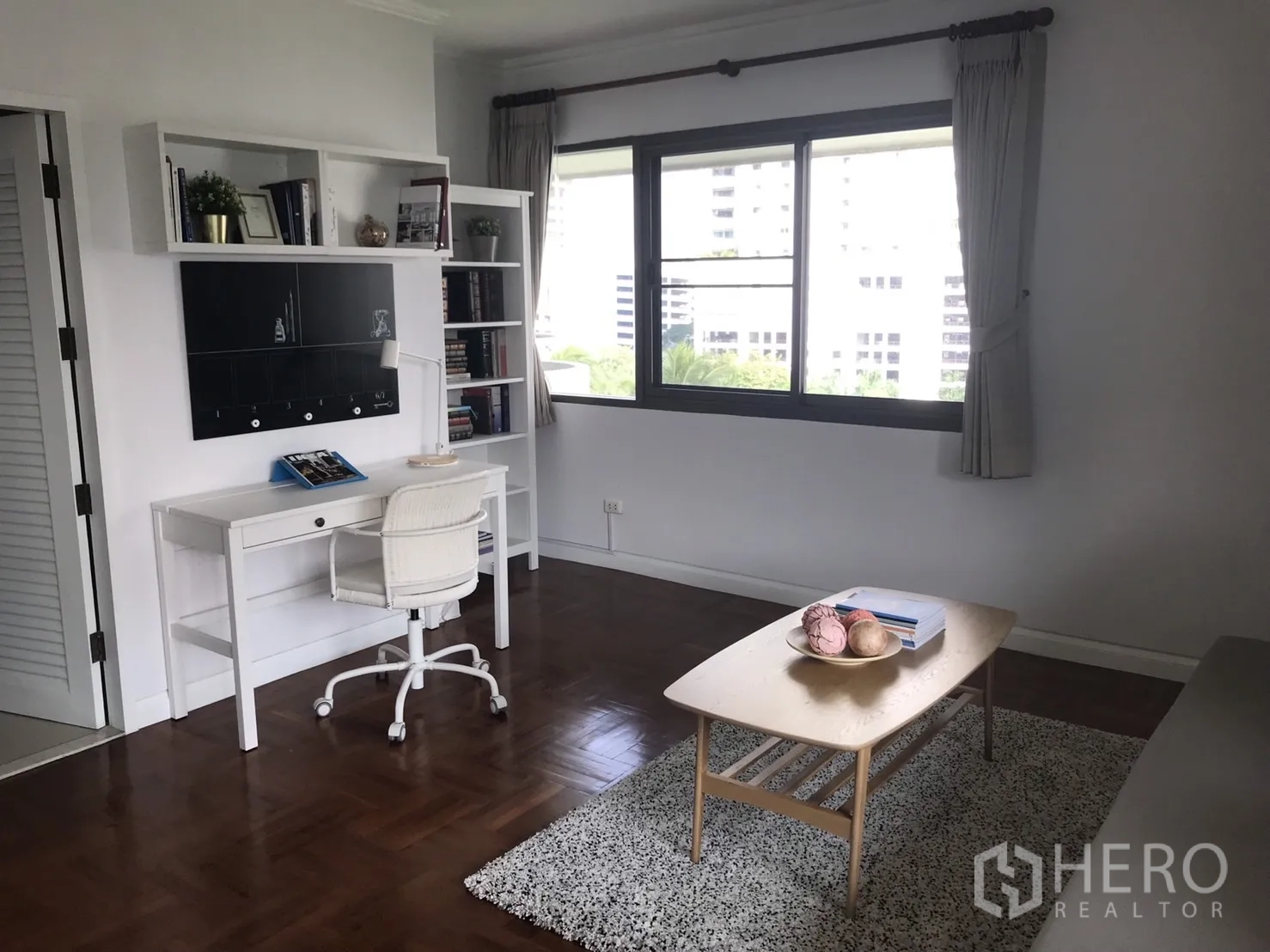 Condominium for rent in Bangkok - Bright study or bedroom with white desk, shelving and a large window.