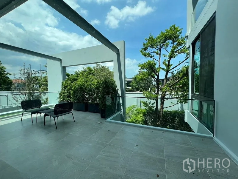 Detached House for rent in Saphan Sung, Bangkok - Spacious terrace with glass balustrade, pergola frame, outdoor seating and lush greenery.
