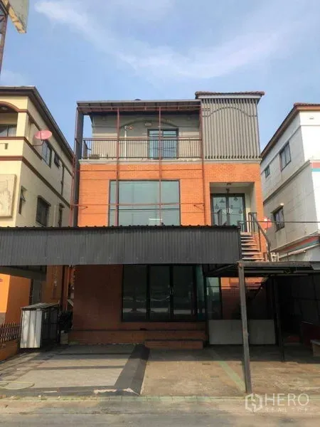 带办公室的家 出售在Min Buri, Bangkok - 三层砖墙与金属立面的家庭办公楼，落地窗，带阳台、外部楼梯和有顶停车位