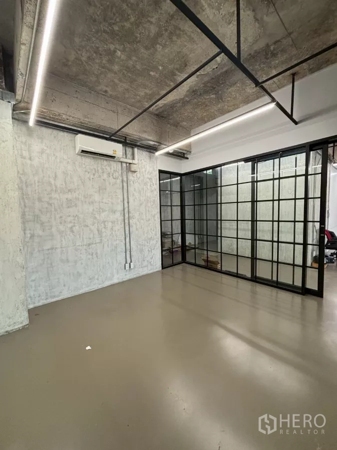 办公空间 出租在Watthana, Bangkok - 室内房间望向黑框玻璃隔断，顶部为外露管线天花。