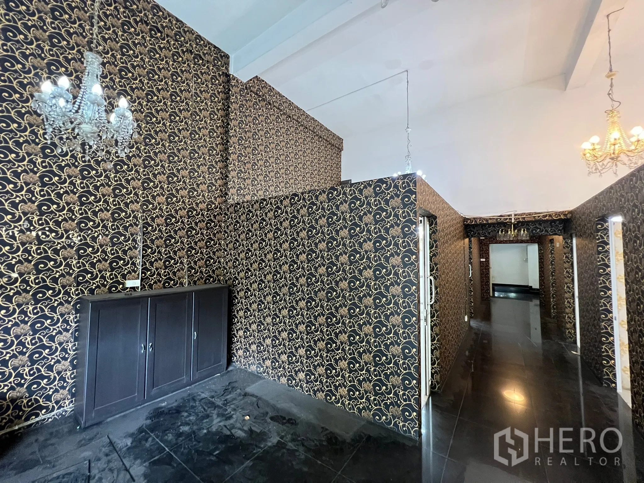 Shophouse for rent in Khlong Toei, Bangkok - Corridor and display area with ornate black-gold wallpaper and a storage cabinet.