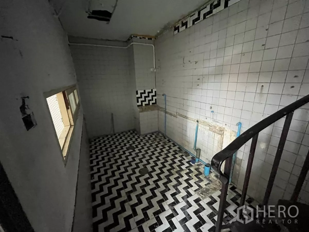 Shophouse for rent in Watthana, Bangkok - Tiled room with a black-and-white herringbone floor and exposed plumbing beside a spiral stair.