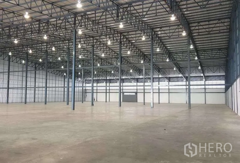 Warehouse for rent in Mueang Samut Prakan, Samut Prakan - Expansive warehouse space with steel structure and evenly spaced industrial lighting.