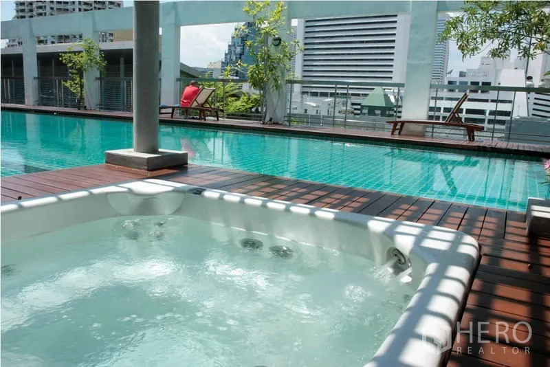 房间 出租在Bang Rak, Bangkok - 屋顶泳池与按摩浴缸，木平台，远望城市天际线。