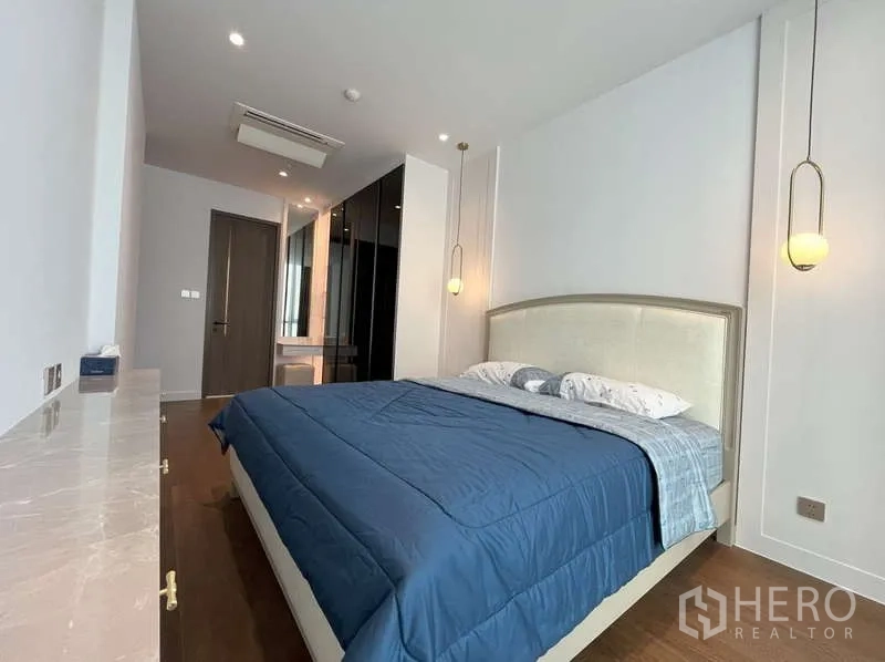 Condominium for rent or sale in Sathon, Bangkok - Master bedroom with pendant lights, king bed and glass-front closets.