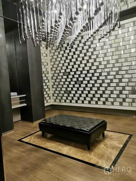 Condominium for rent in Watthana, Bangkok - Stylish lounge area with statement chandelier, tufted bench and mirrored feature wall.
