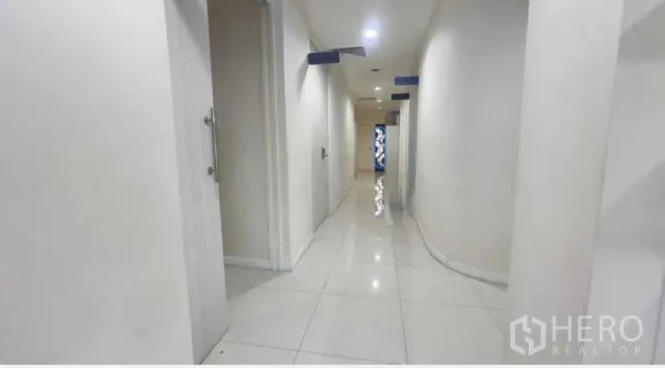 Standalone for rent in Khlong Toei, Bangkok - Bright white corridor with tiled floors and multiple doors leading to rooms.