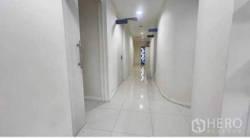 Standalone for rent in Khlong Toei, Bangkok - Bright white corridor with tiled floors and multiple doors leading to rooms.