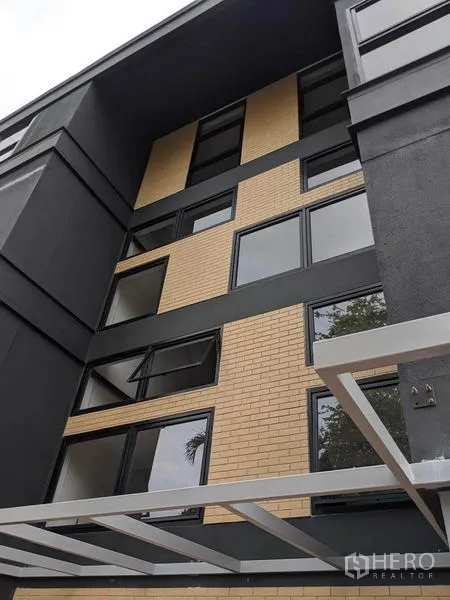 Home Office for rent or sale in Phaya Thai, Bangkok - Close-up of exterior showing brick accents and dark cladding around windows.