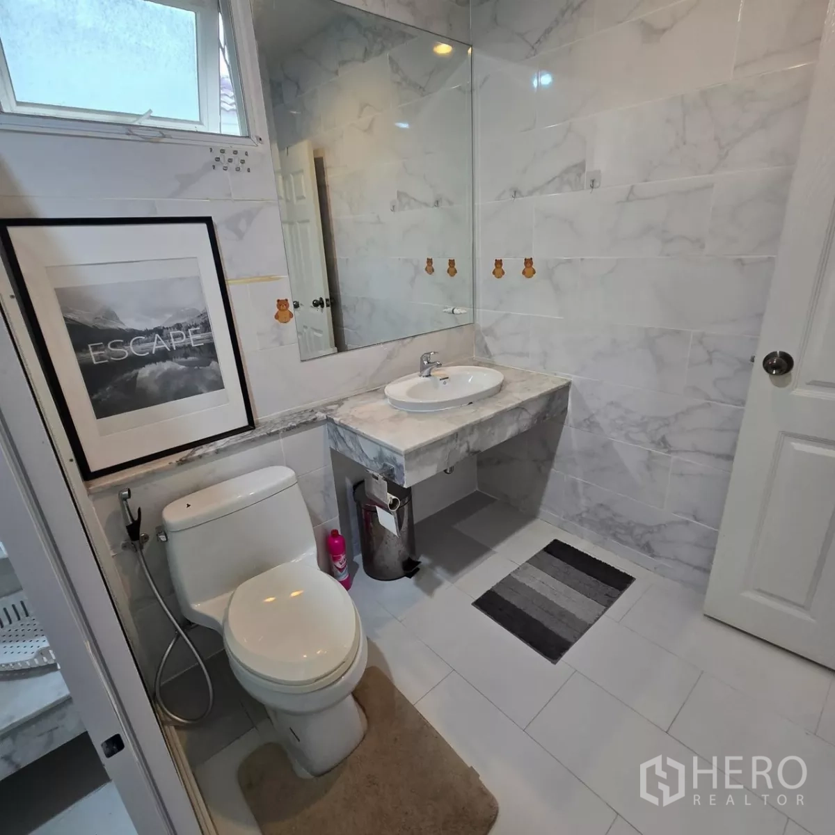 Detached House for rent in Mueang Pathum Thani, Pathum Thani - Vanity and toilet in a marble-tiled bathroom with a large mirror.