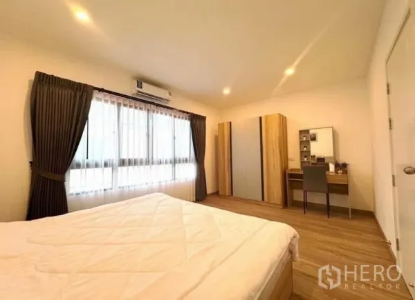 Townhouse for rent - Second bedroom with big window, wardrobe, dressing table, and wood flooring.
