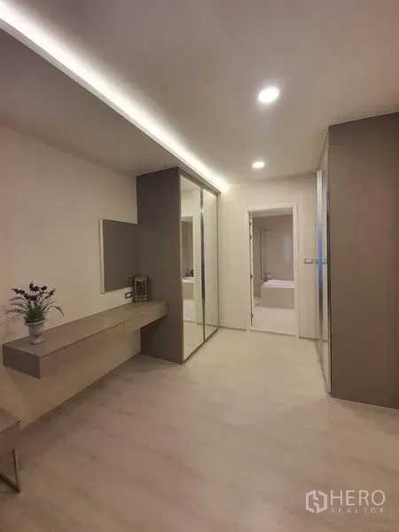 Condominium for rent in Khlong Toei, Bangkok - Dressing area with wall mirror, built-in desk, sliding glass wardrobe and doorway to ensuite.