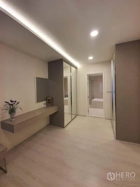 Condominium for rent in Khlong Toei, Bangkok - Dressing area with wall mirror, built-in desk, sliding glass wardrobe and doorway to ensuite.
