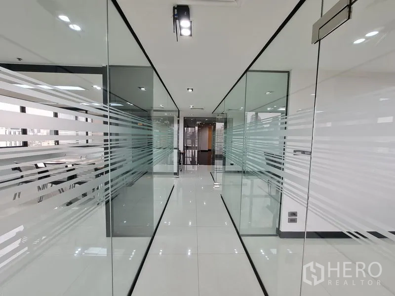 Office Space for rent in Bang Rak, Bangkok - Sleek hallway featuring frosted-stripe glass partitions and polished white tiles.