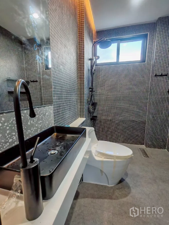 Detached House for rent in Wang Thonglang, Bangkok - Bathroom with long black countertop basin, mosaic walls, and toilet.
