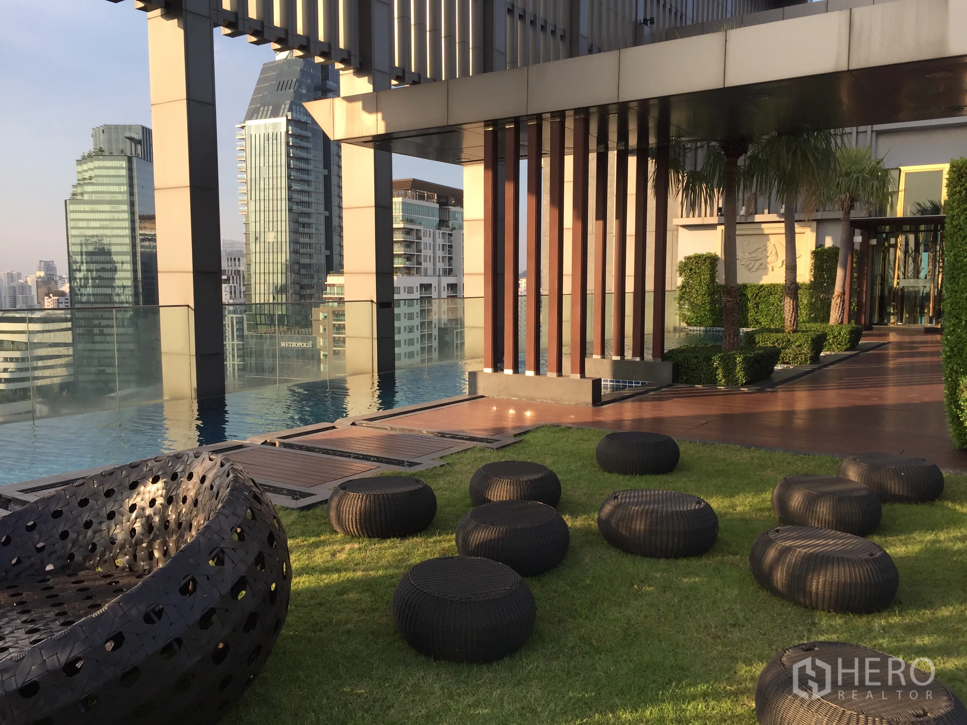 คอนโด ให้เช่าหรือขายในKhlong Toei, Bangkok - เลานจ์สวนดาดฟ้า เก้าอี้หวาย ราวกระจก เห็นสกายไลน์กรุงเทพฯ ข้างสระว่ายน้ำ