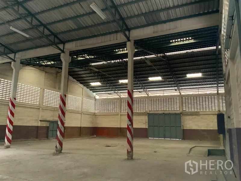 คลังสินค้า ให้เช่าในBang Kapi, Bangkok - ภายในโกดังเพดานสูง โครงเหล็ก เสาลายแดงขาว ผนังบล็อกช่องลม และประตูเหล็กบานคู่