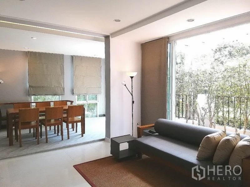 Townhouse for rent or sale in Suan Luang, Bangkok - Open-plan living and dining zone with sofa, floor lamp and garden view.