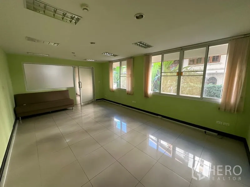 Office Space for sale - Corner office with large windows, green walls, whiteboard and glass door.