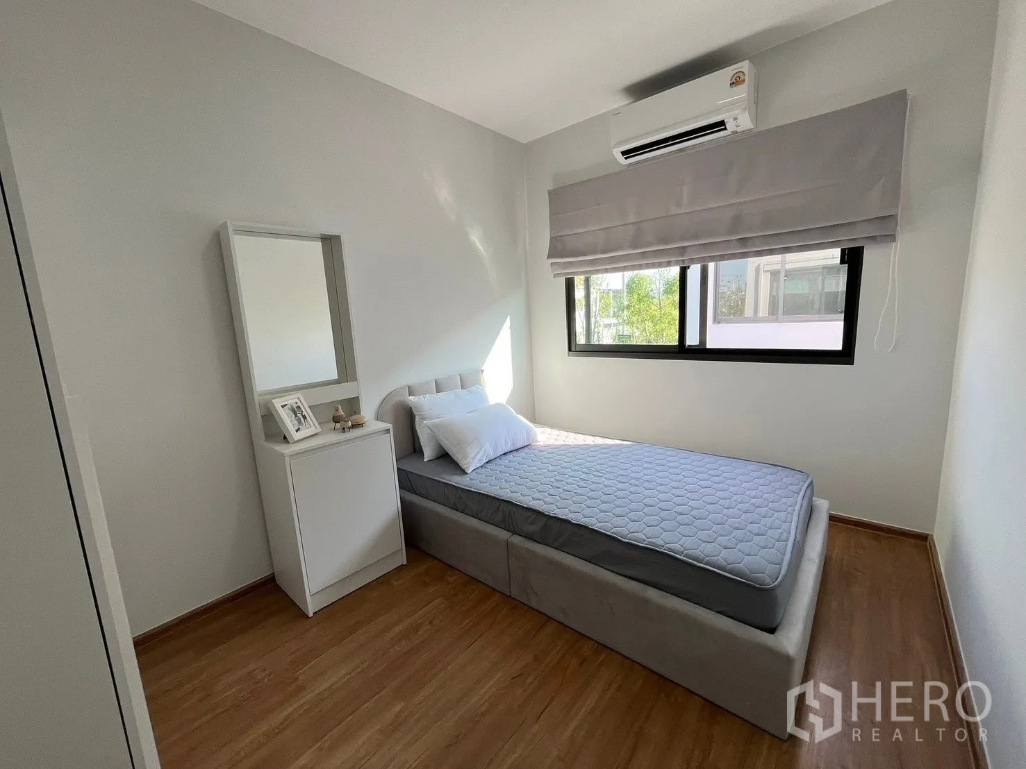 Townhouse for rent in Bang Phli, Samut Prakan - Cozy bedroom with single bed, large window with Roman shade, and wall-mounted air conditioner.