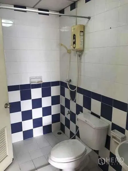 Townhouse for rent in Suan Luang, Bangkok - Bathroom with blue and white checker tiles, toilet, handheld shower and electric water heater.