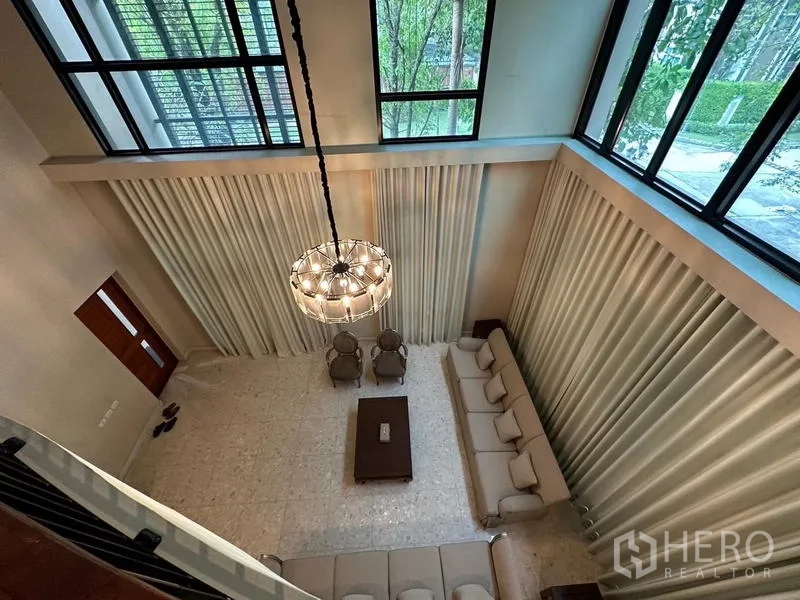 Detached House for rent or sale in Khan Na Yao, Bangkok - Aerial view of chandelier and double-volume living room with tall drapes.