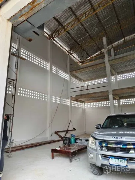 Warehouse for rent in Phra Khanong, Bangkok - High-clearance warehouse interior with insulated steel roof, tall white columns, and a pickup access bay.