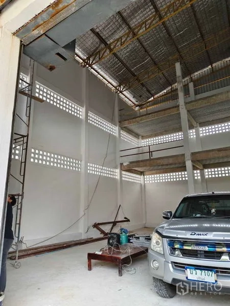 Warehouse for rent in Phra Khanong, Bangkok - High-clearance warehouse interior with insulated steel roof, tall white columns, and a pickup access bay.