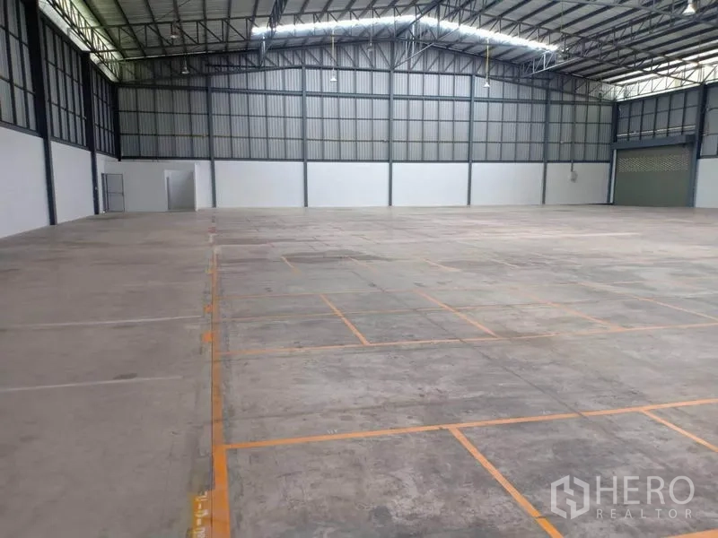 Warehouse for rent in Lat Krabang, Bangkok - Open storage floor with marked pallet bays beneath a high-clear roof and bright lighting.