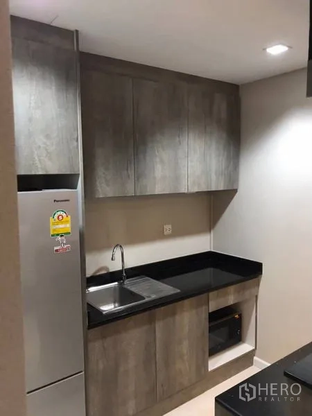 Detached House for rent in Thanyaburi, Pathum Thani - Compact pantry kitchen with grey cabinets, black countertop, sink, and refrigerator.