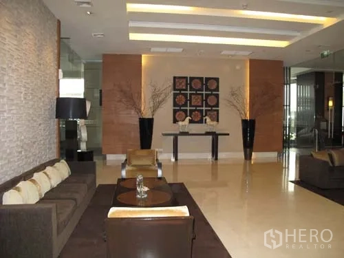 Condominium for rent in Sathon, Bangkok - Modern condominium lobby with sofas, accent lighting and decorative wall art.