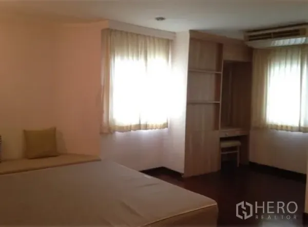 公寓 出租在Watthana, Bangkok - 转角卧室，双面窗户、内置书桌与书架，轻薄窗帘。