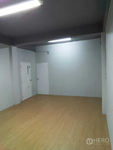Shophouse for rent in Khlong Toei, Bangkok - Open-plan white room with timber floor and fluorescent lighting inside the shophouse.