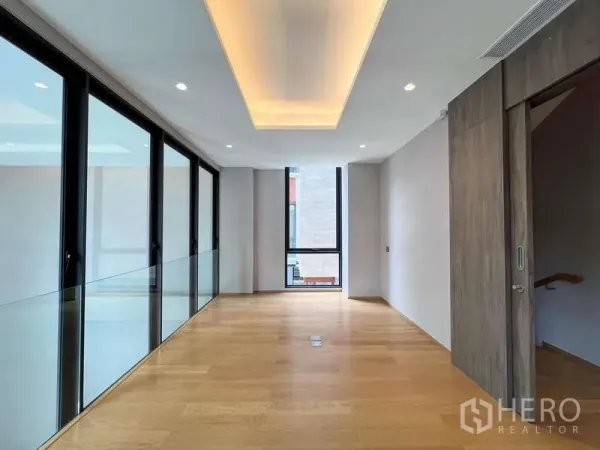 独立式住宅 出售在Yan Nawa, Bangkok - 二层走廊，木地板、嵌灯与整面落地玻璃
