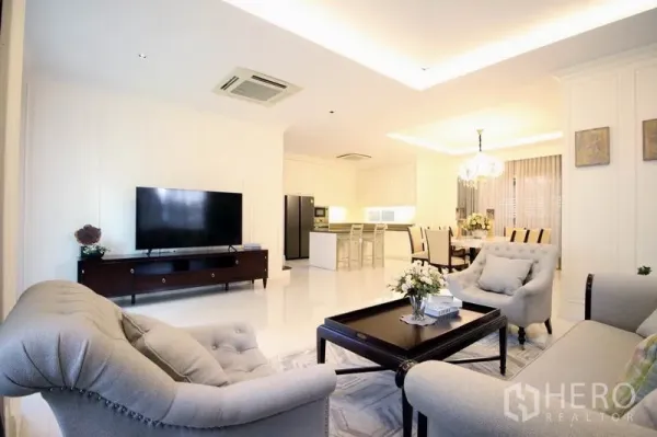 Detached House for rent or sale - Open-plan living area with sofas, TV console, island kitchen and dining space under recessed lighting.
