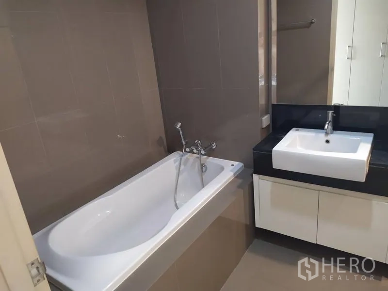 Condominium for sale in Khlong Toei, Bangkok - Bathroom view with a full bathtub and wide vanity with mirror.