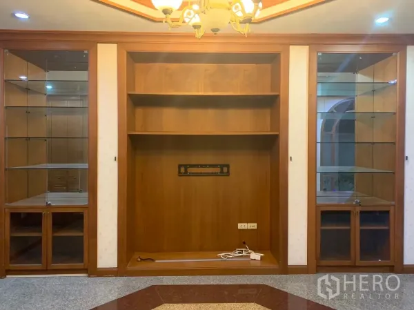 Detached House for rent in Watthana, Bangkok - Built-in wooden wall unit with glass display cabinets in the living room.
