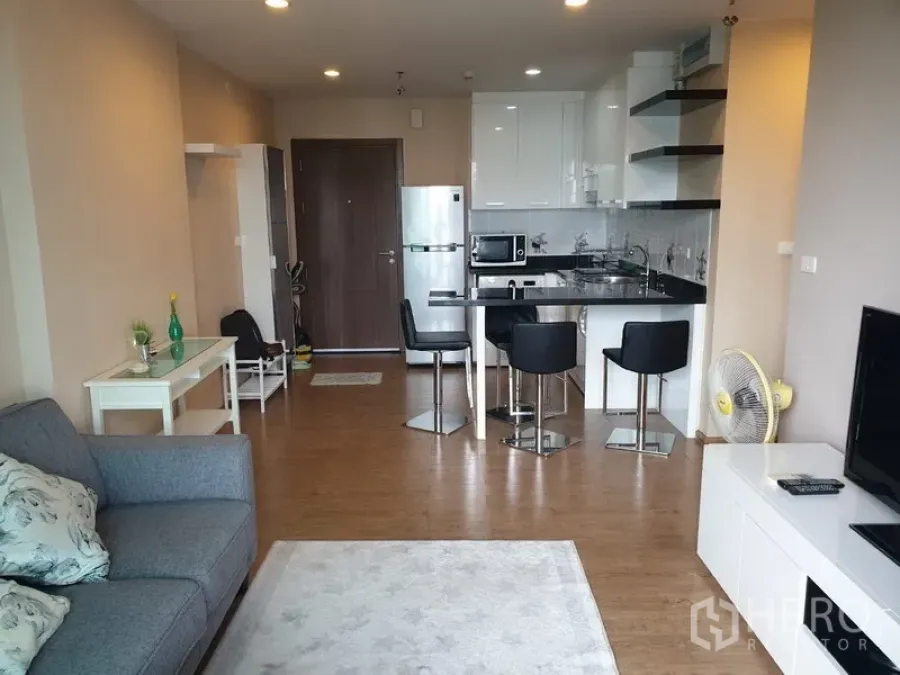 公寓 出租在Watthana, Bangkok - 开放式客厅，配沙发、电视柜与带吧台的现代厨房