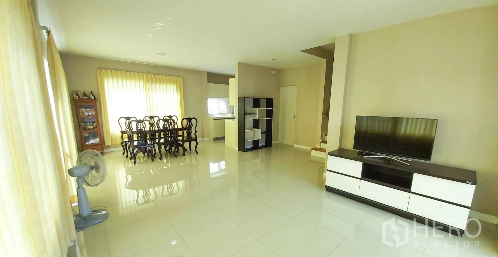 Detached House for sale in Bang Kapi, Bangkok - Expansive living space with TV console and dining set beside full-height windows.