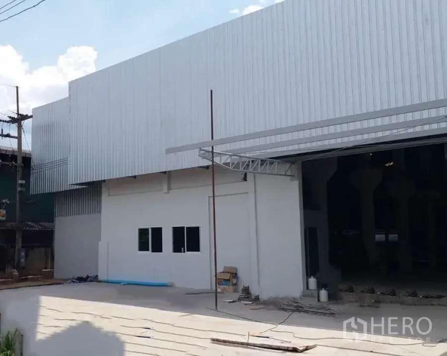 โรงงาน ให้เช่าในKrathum Baen, Samut Sakhon - ด้านหน้าอาคารโรงงานผนังเมทัลชีท พร้อมลานจอดและช่องเปิดขนาดใหญ่สำหรับขนถ่ายสินค้า
